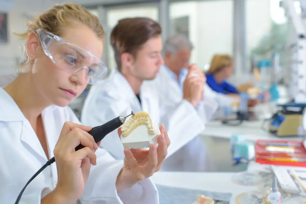 Woman shaping false teeth using an electric tool