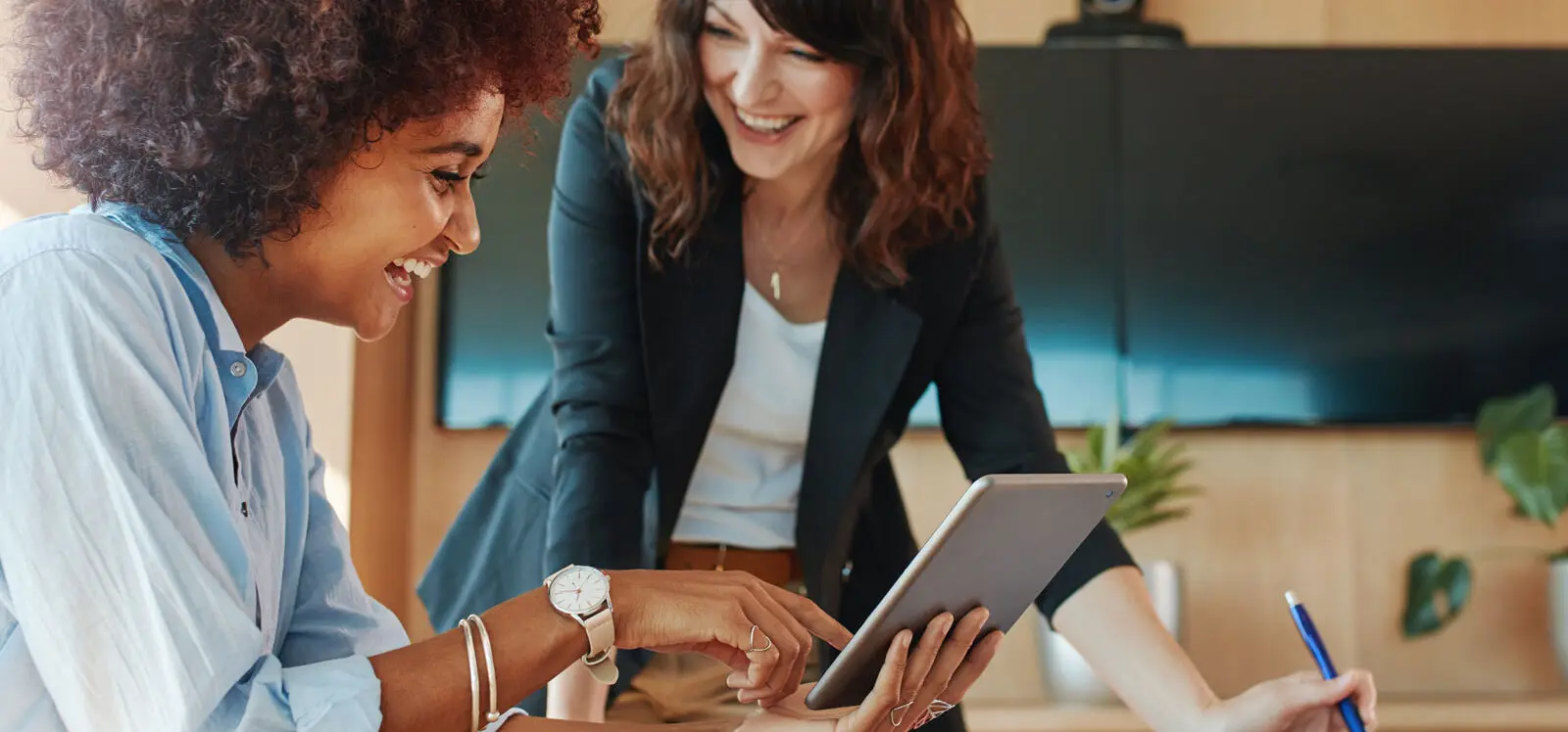 two women laughing with tablet