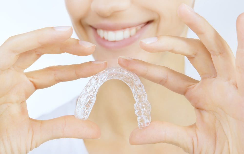 Beautiful smiling girl with tooth tray (hands holding individual tooth tray)