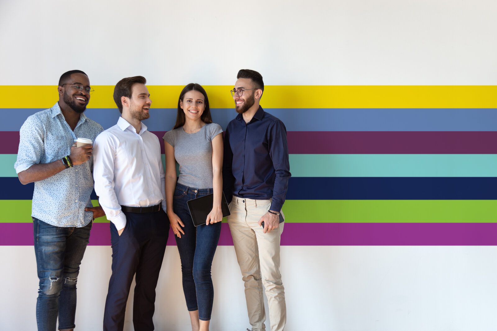 Four diverse young business people pose near grey white wall studio background copy space for ad text, millennial generation arab african european professionals, human resources, new workforce concept